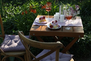 Photo of Vase with spring flowers, wine and cake on table served for romantic date in garden