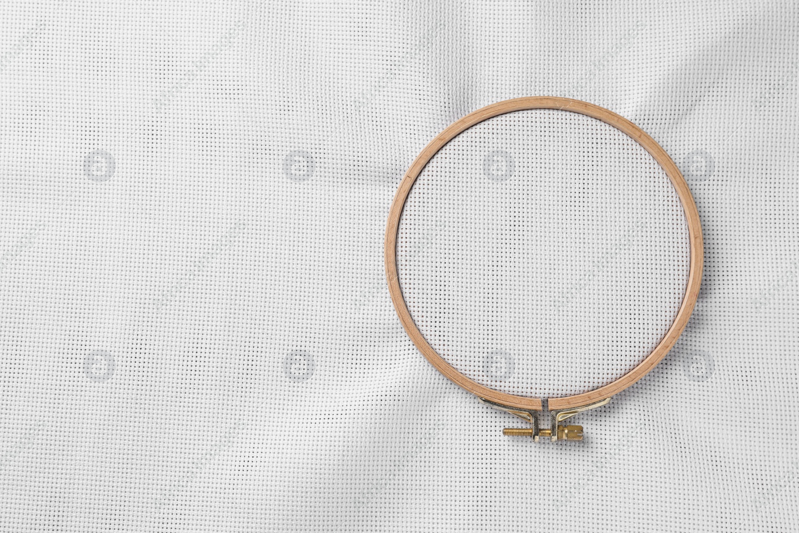 Photo of Embroidery hoop with white fabric stretched as background, top view. Space for text