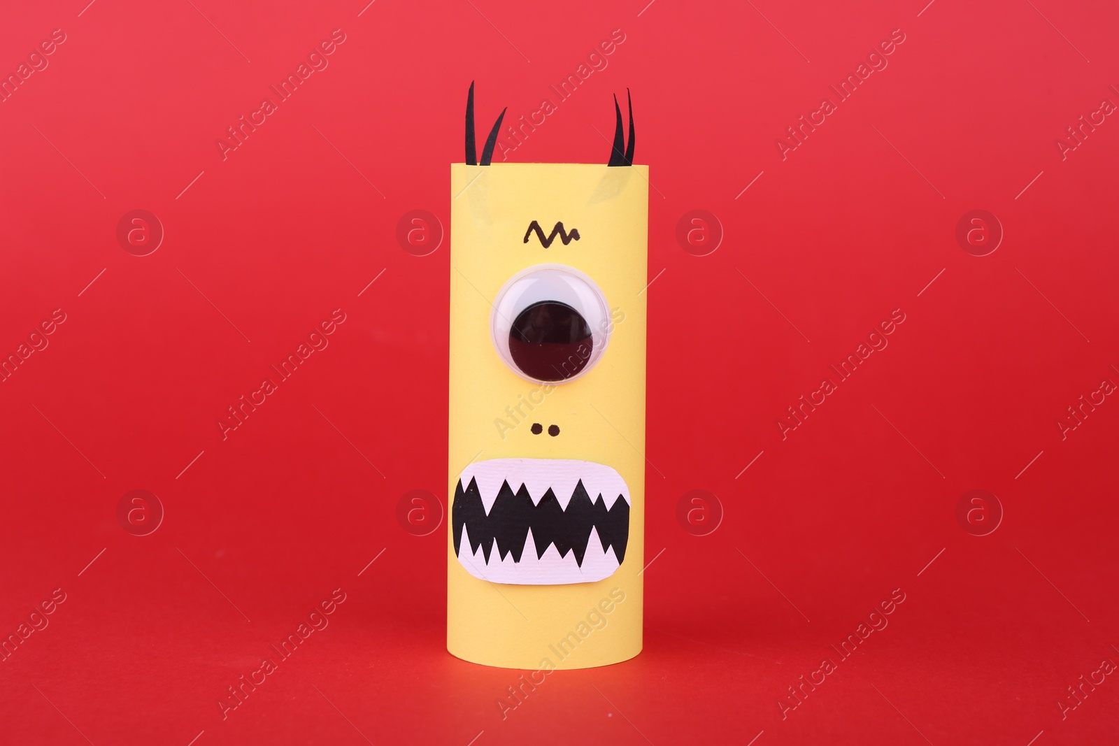 Photo of Spooky paper monster on red background. Handmade Halloween decoration