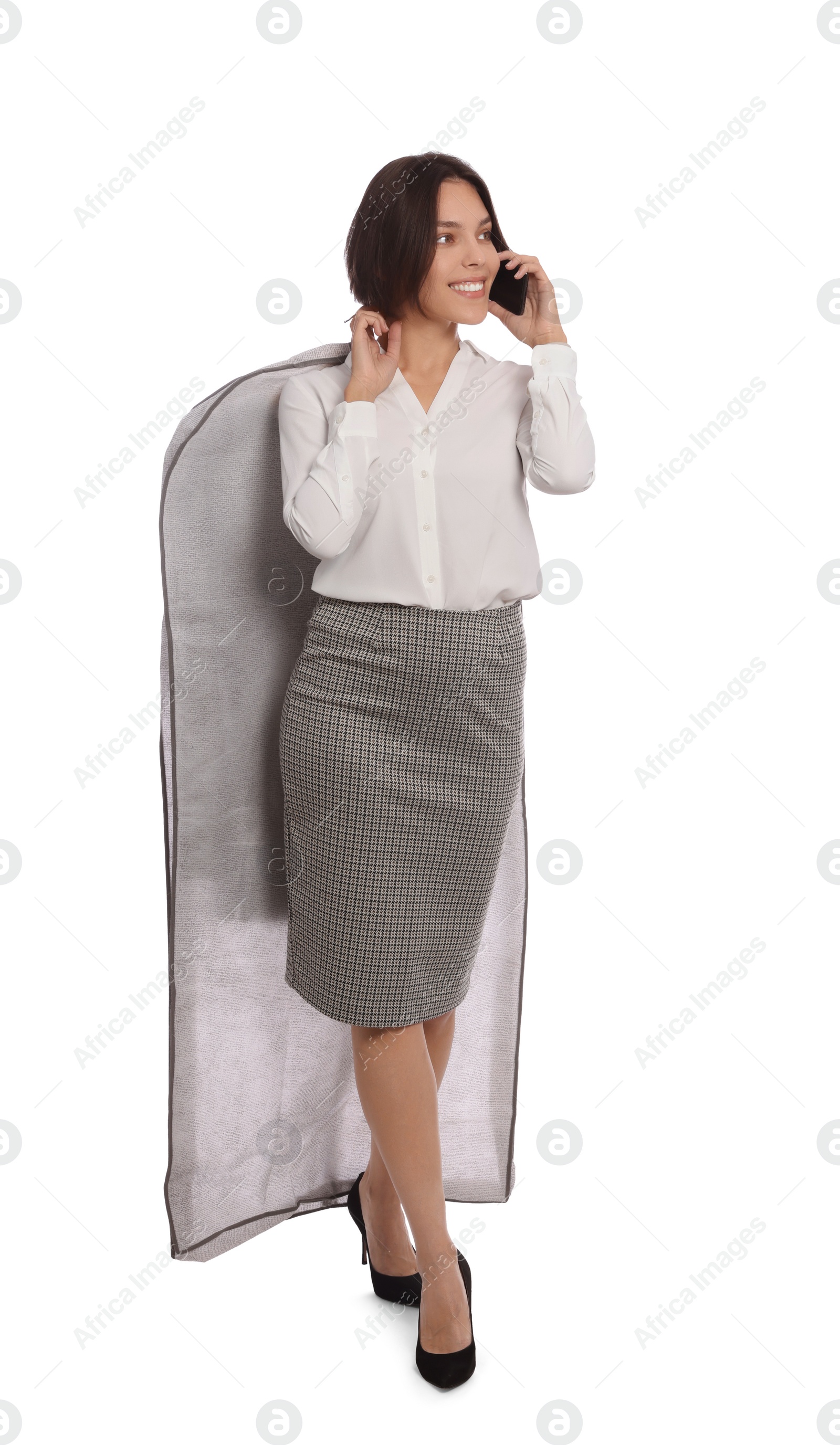 Photo of Woman holding garment cover with clothes while talking on phone, isolated on white. Dry-cleaning service