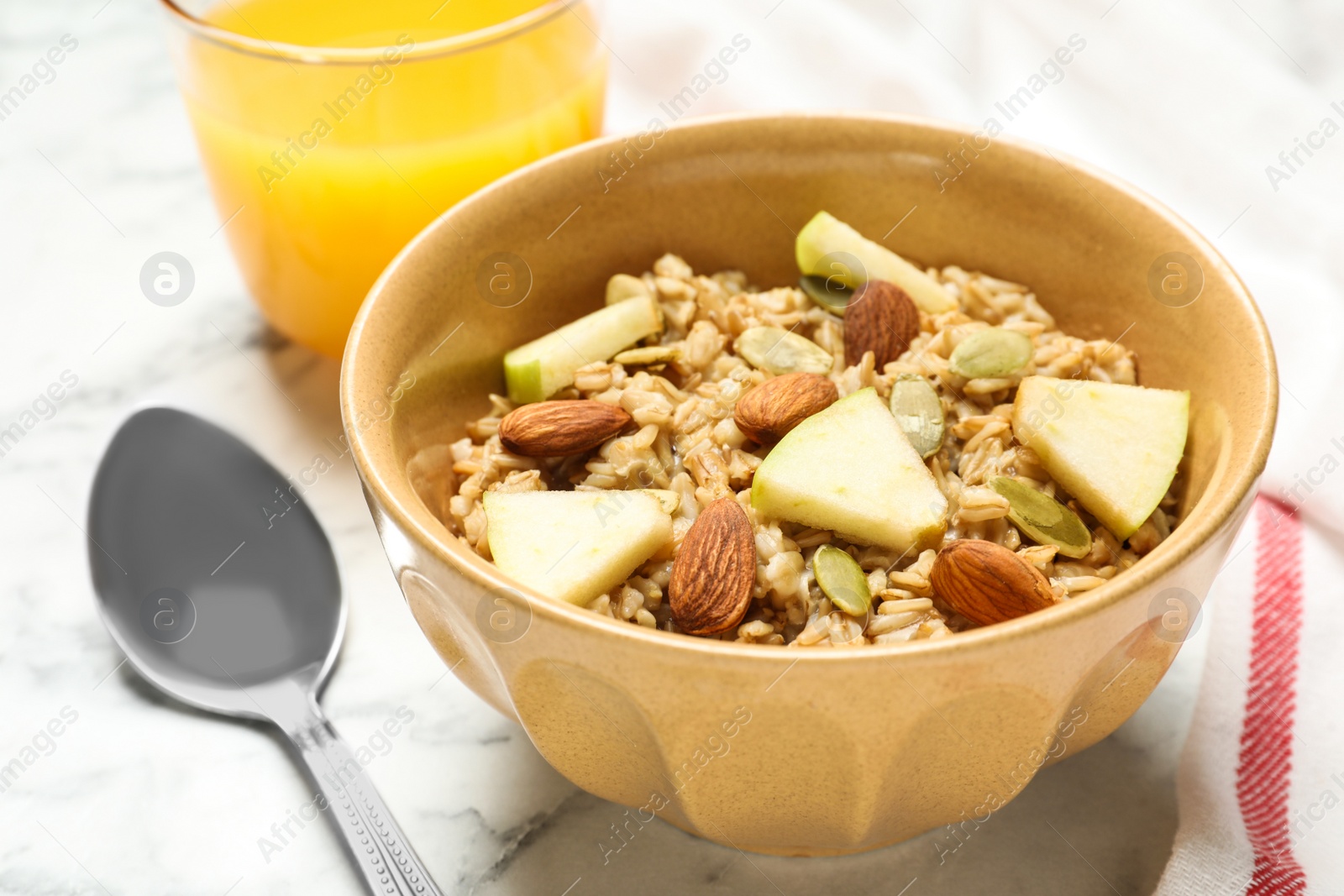 Photo of Tasty oatmeal with apples and almonds on marble table, closeup. Healthy breakfast