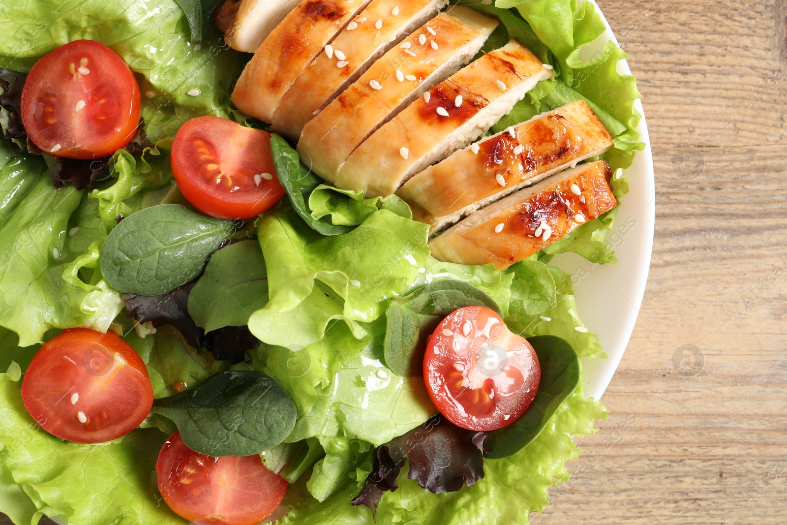 Photo of Delicious salad with chicken, cherry tomato and spinach on wooden table, top view