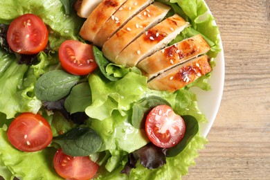 Photo of Delicious salad with chicken, cherry tomato and spinach on wooden table, top view