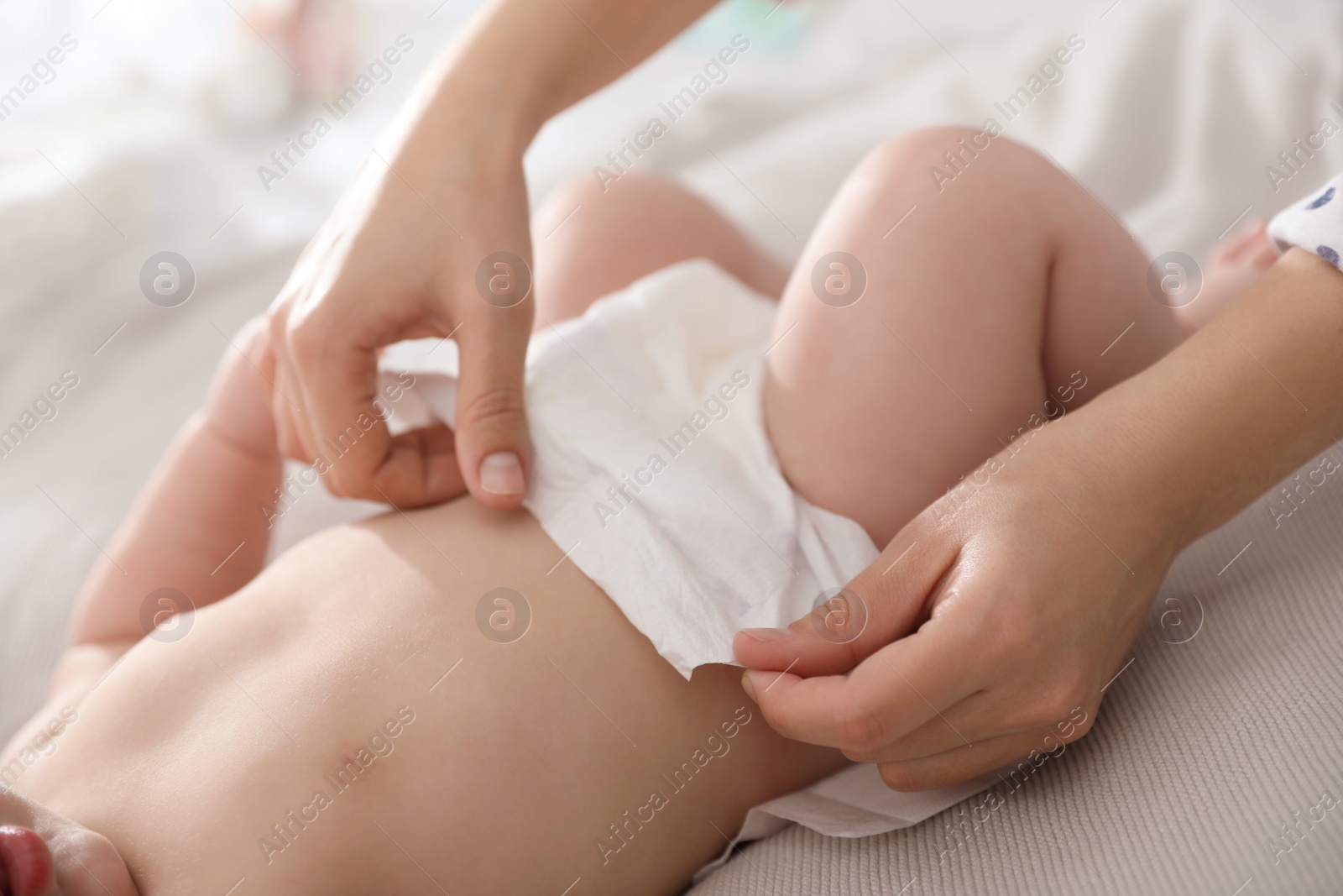 Photo of Mother changing her baby's diaper on bed, closeup