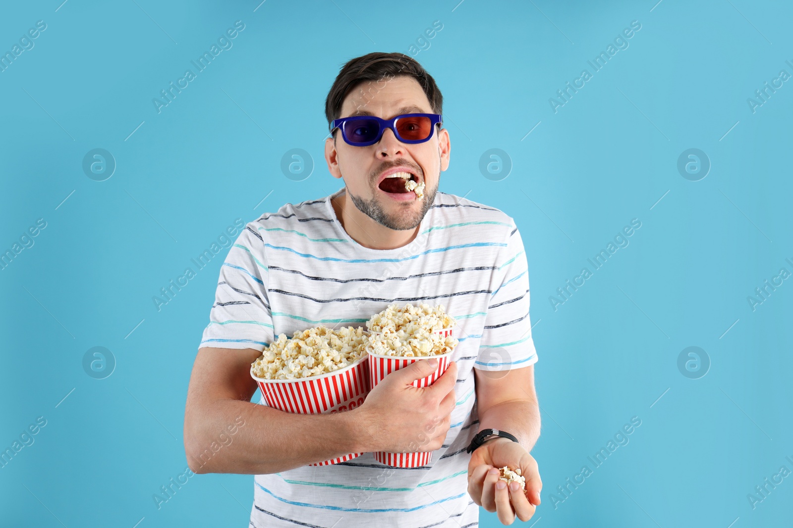 Photo of Man with 3D glasses eating tasty popcorn on color background