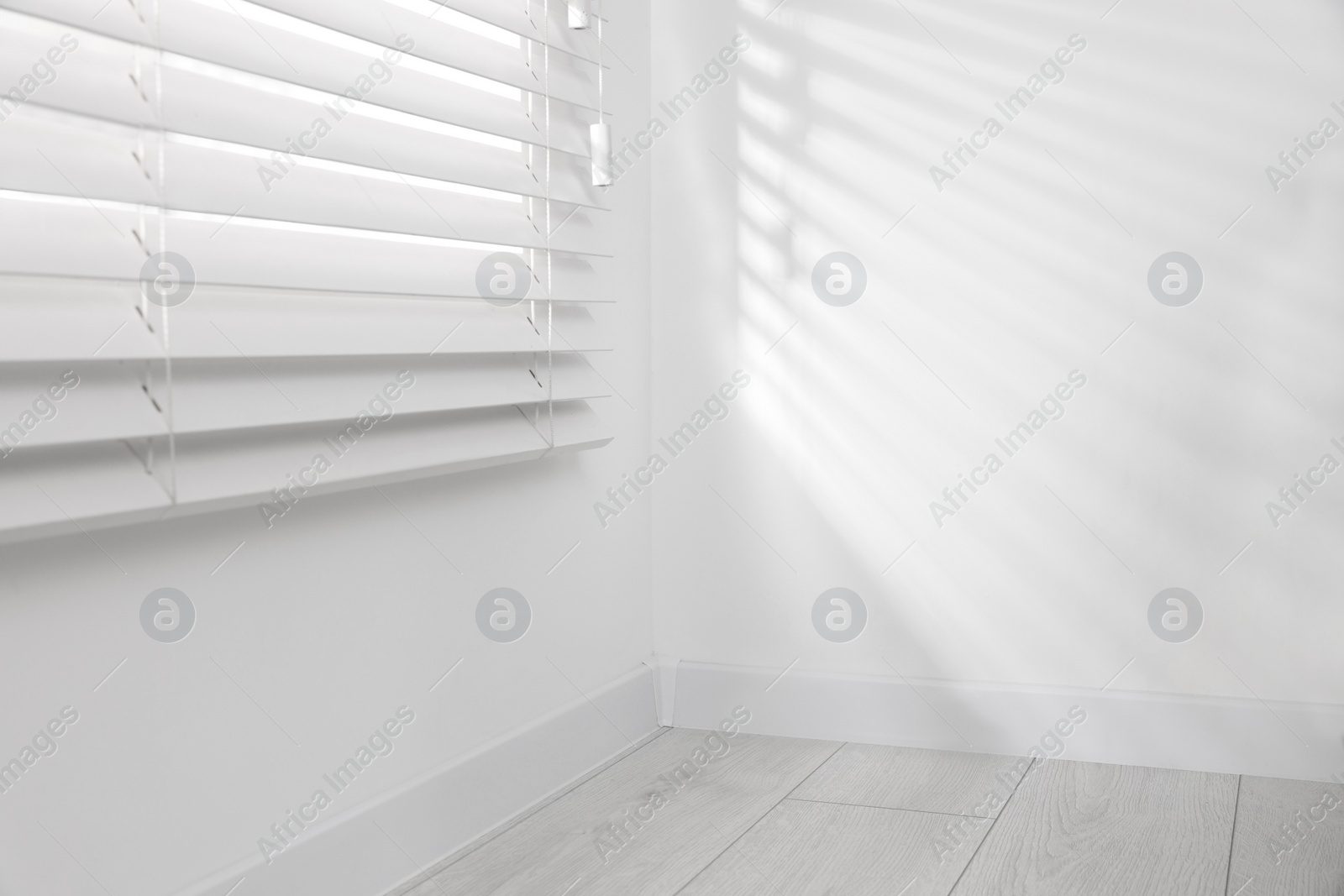 Photo of Window with closed horizontal blinds near white wall indoors