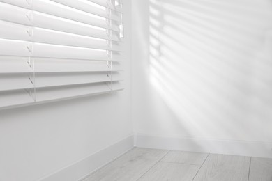 Photo of Window with closed horizontal blinds near white wall indoors