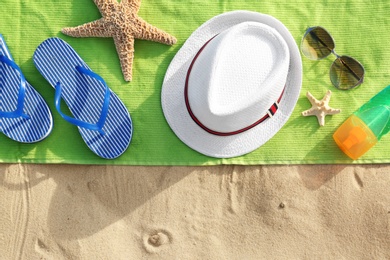 Flat lay composition of beach objects and towel on sand, space for text