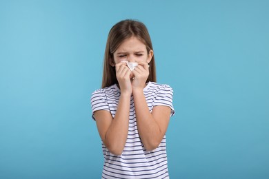 Photo of Sick girl with tissue coughing on light blue background