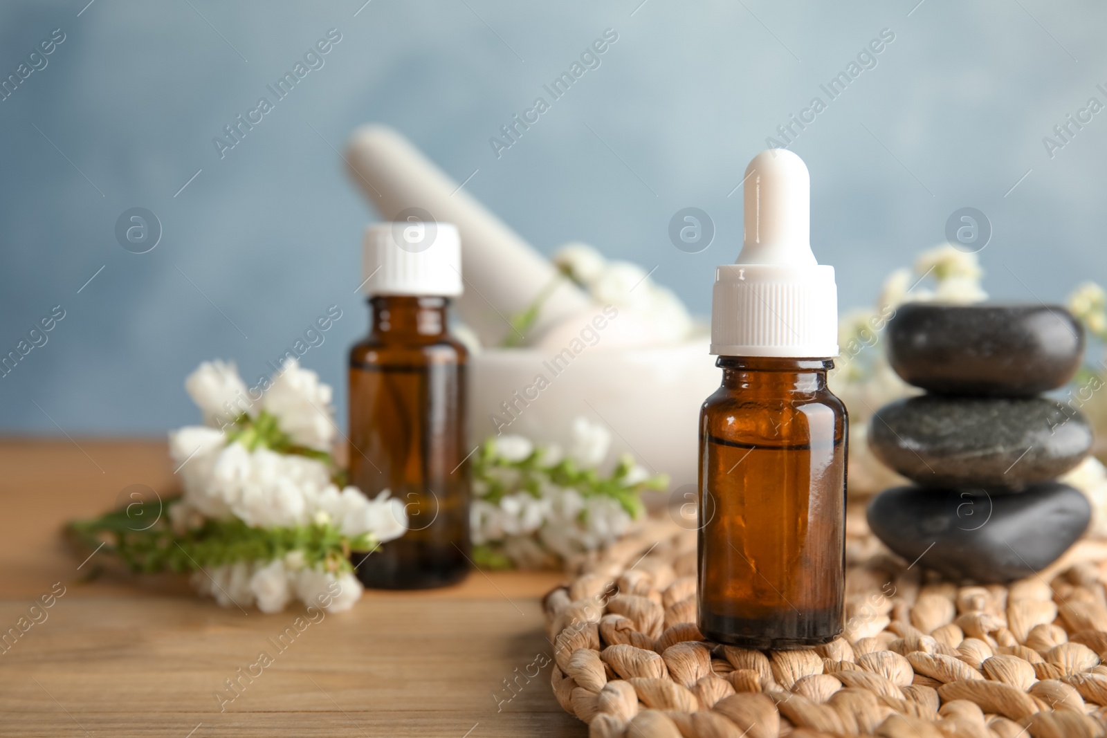 Photo of Composition with essential oil, spa stones and flowers on table