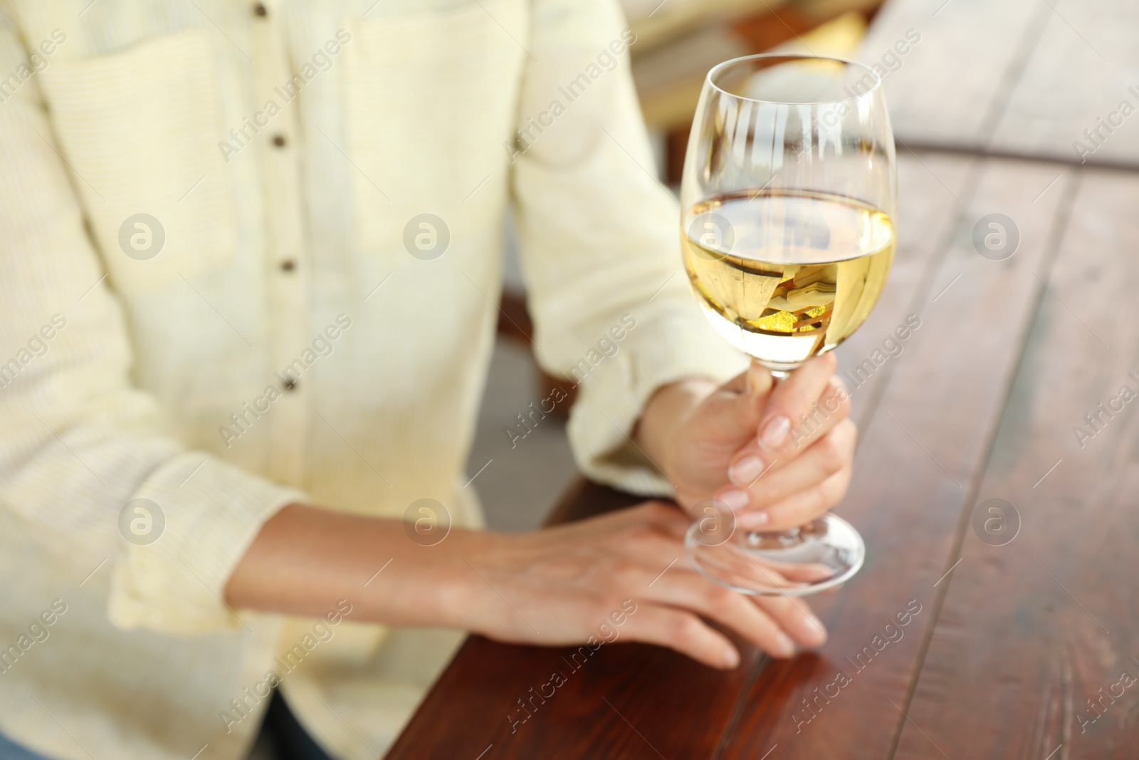 Photo of Woman with glass of white wine in outdoor cafe, closeup