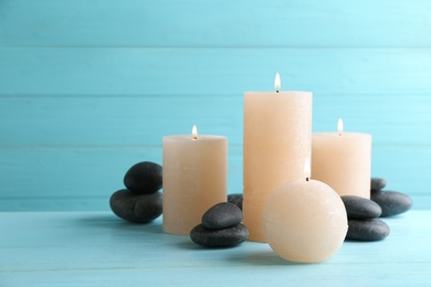 Photo of Composition of burning candles and spa stones on table. Space for text