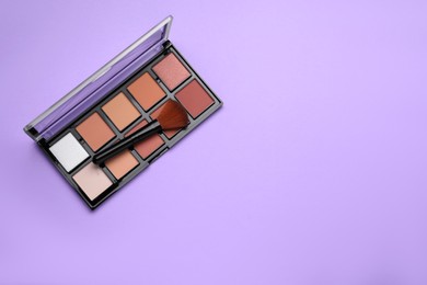 Photo of Colorful contouring palette and brush on violet background, top view with space for text. Professional cosmetic product