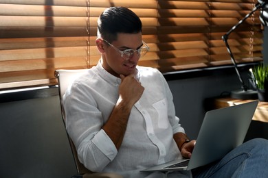 Photo of Freelancer working on laptop near window indoors