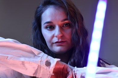 Photo of Portrait of beautiful young woman on color background with neon lights