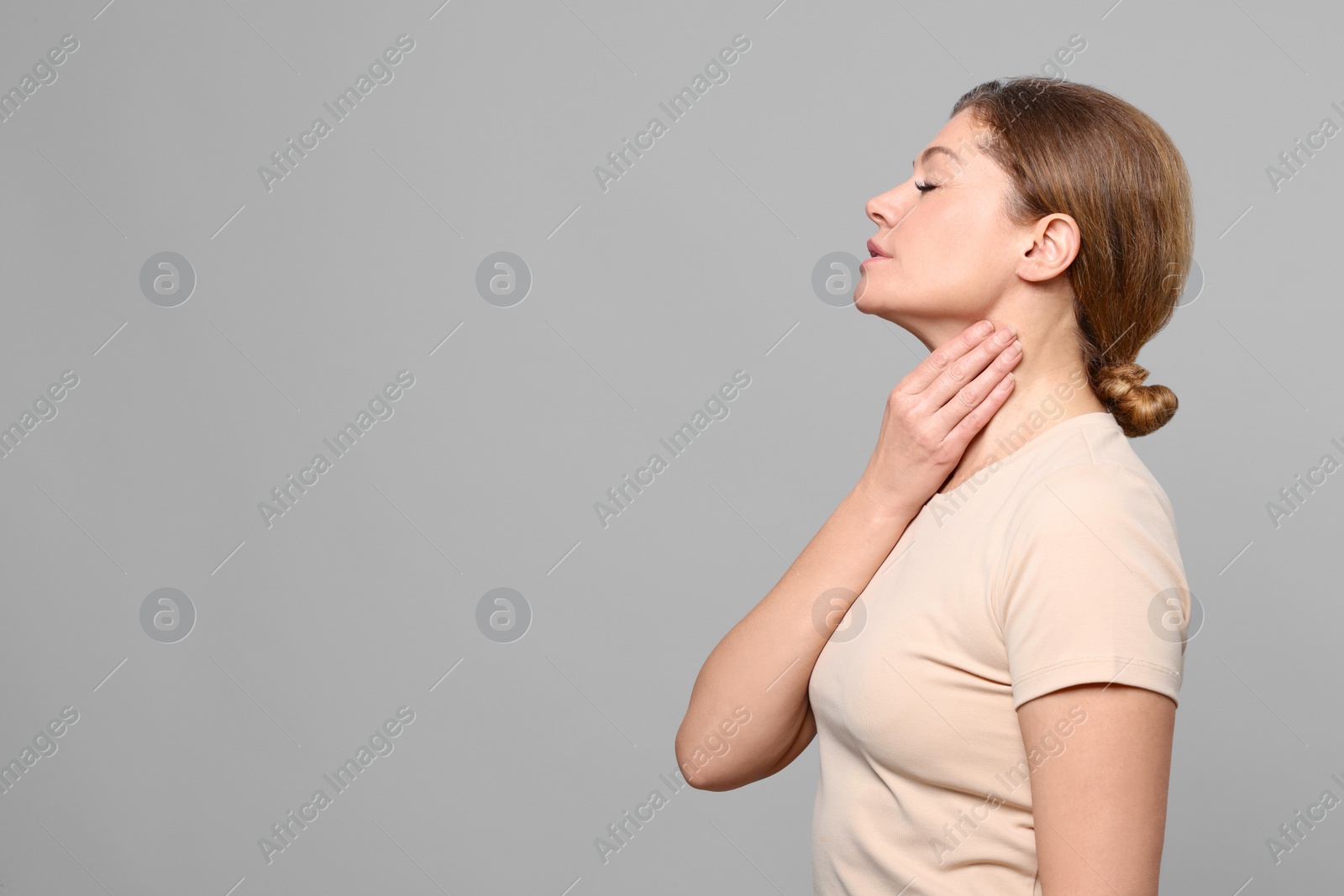 Photo of Woman suffering from sore throat on light grey background. Space for text