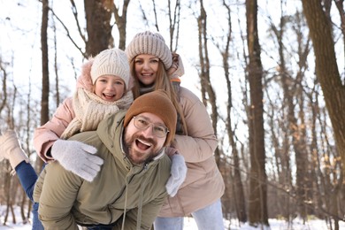 Photo of Happy family spending time together in snowy forest. Space for text