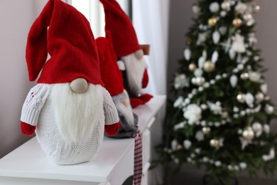 Photo of Cute Christmas gnomes on white table in room with festive decorations. Space for text