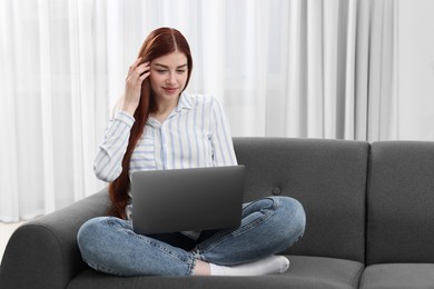 Photo of Beautiful woman using laptop on couch indoors