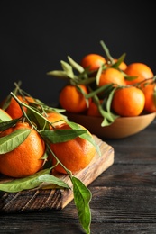 Wooden board with ripe tangerines on table. Space for text