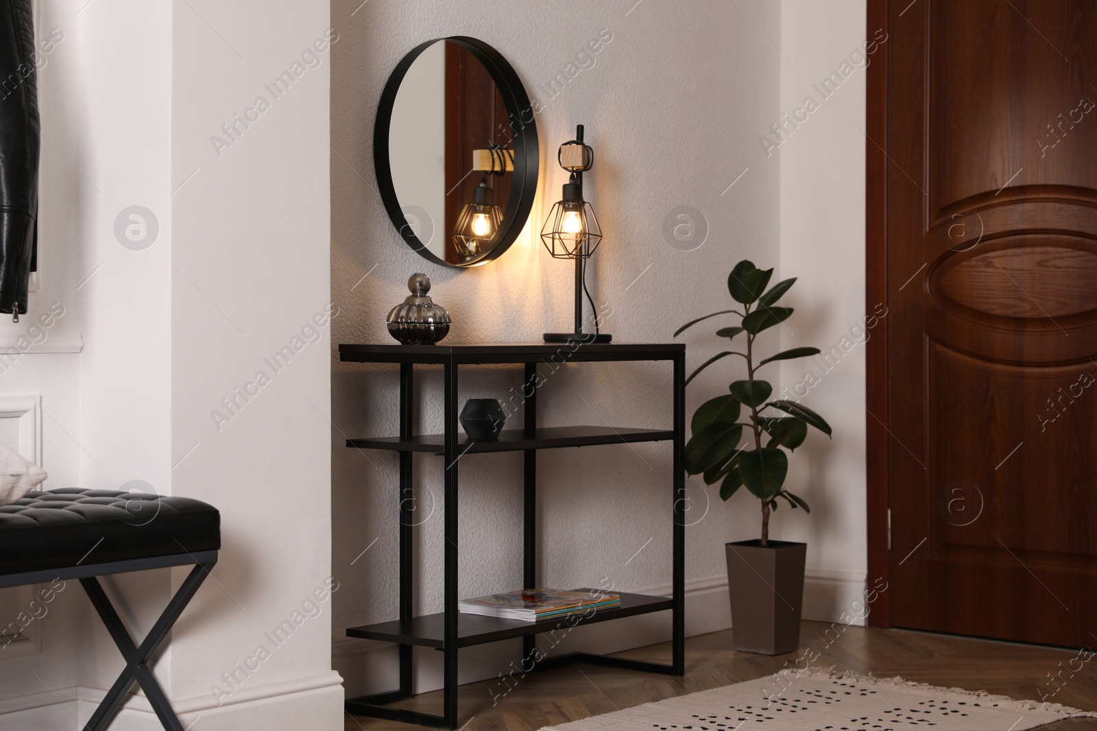 Photo of Console table with decor and mirror on white wall in hallway. Interior design