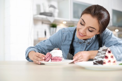 Photo of Professional female chef presenting dessert on table in kitchen