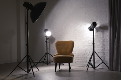 Interior of modern photo studio with professional lighting equipment and armchair