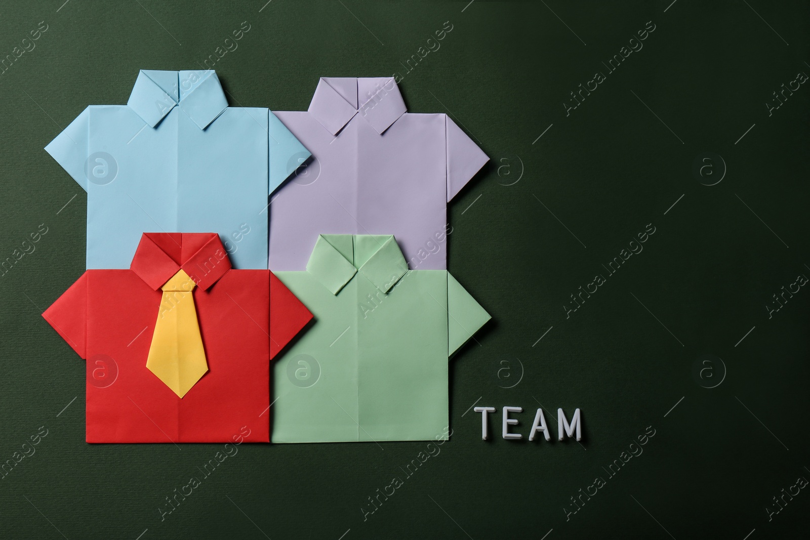 Photo of Many paper shirts and word Team on green background, flat lay with space for text. Recruiter searching employee