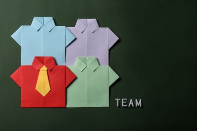 Photo of Many paper shirts and word Team on green background, flat lay with space for text. Recruiter searching employee