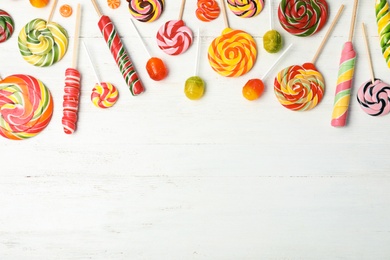 Different colorful candies and space for text on white wooden background, top view