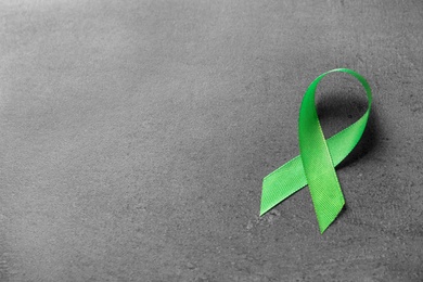 Photo of Green ribbon on grey background. Cancer awareness