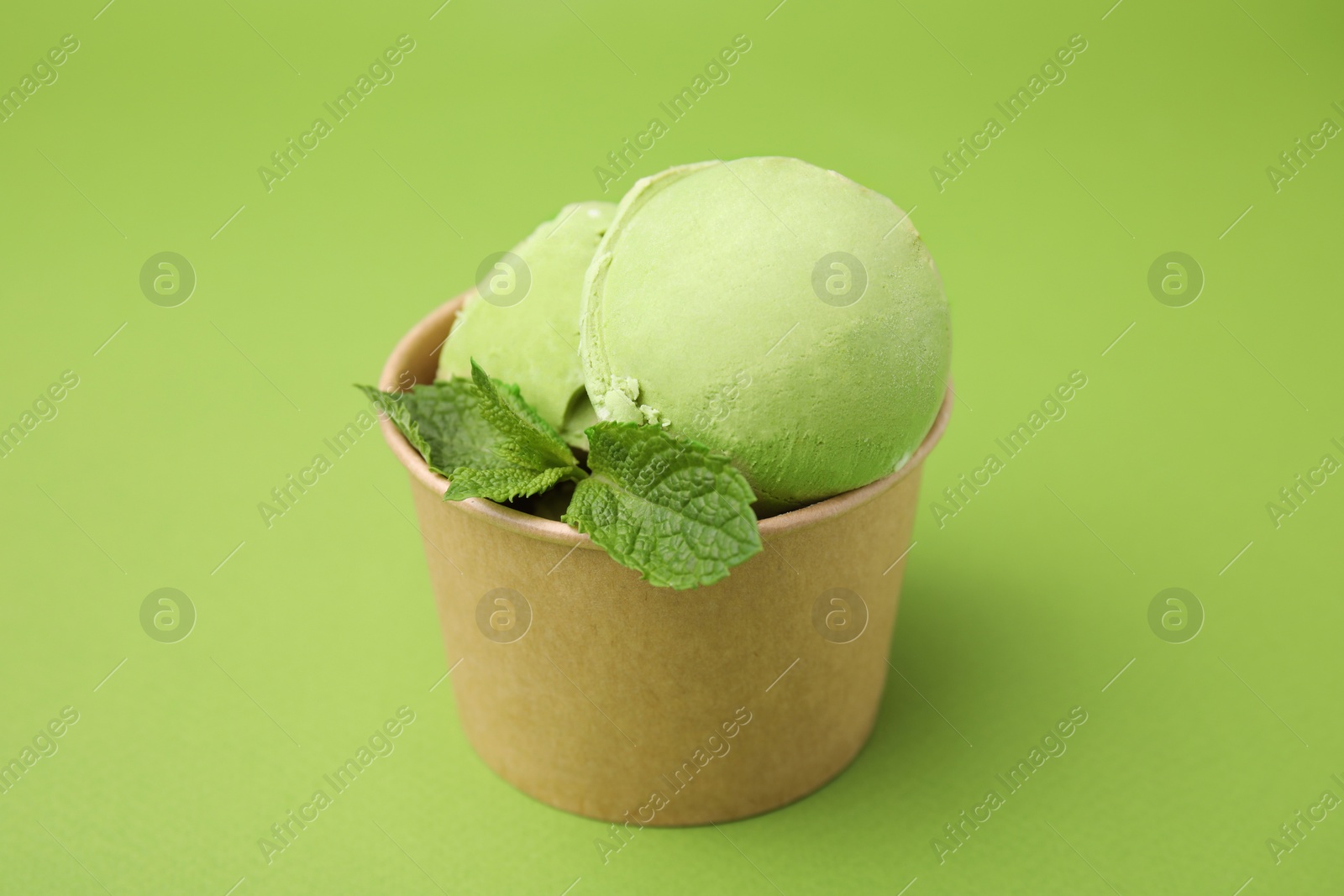 Photo of Paper cup with tasty matcha ice cream on light green background