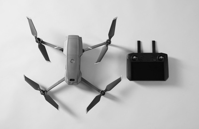 Photo of Modern drone with controller on light background, top view
