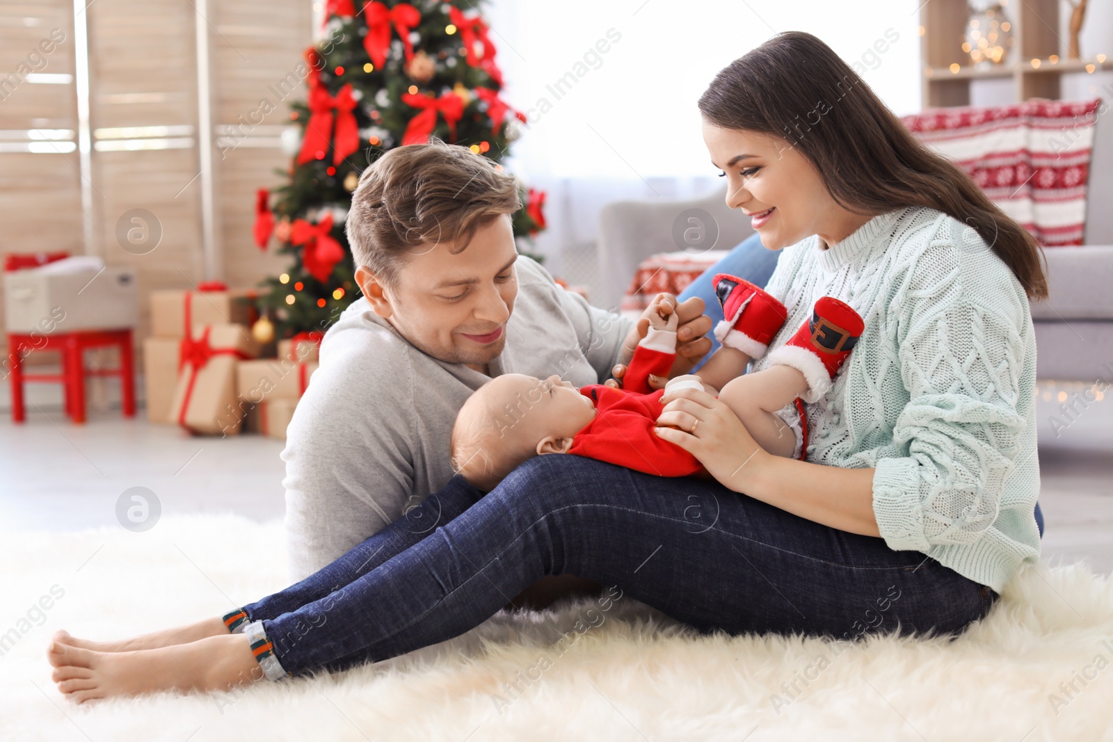 Photo of Happy couple with baby celebrating Christmas together at home