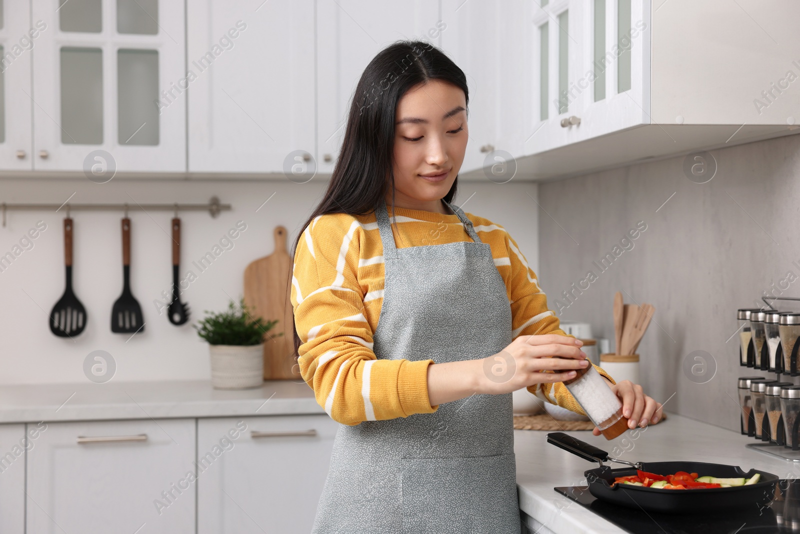 Photo of Beautiful woman cooking vegetable dish in kitchen. Space for text