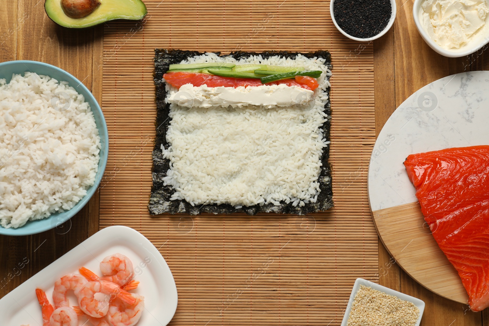 Photo of Flat lay composition with unwrapped sushi roll and products on wooden table