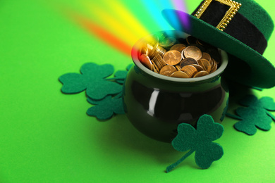 Pot with gold coins, hat and clover leaves on green background, space for text. St. Patrick's Day celebration