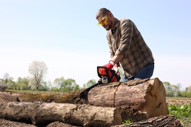 Photo of Man sawing wooden log on sunny day