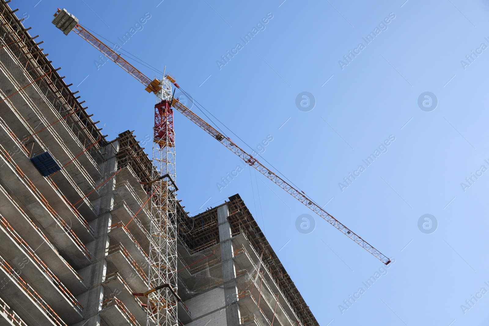 Photo of Construction site with tower crane near unfinished building, low angle view