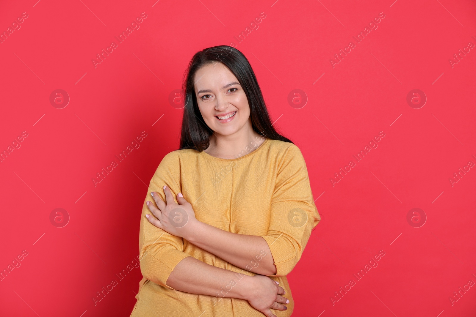 Photo of Beautiful overweight woman with charming smile on red background