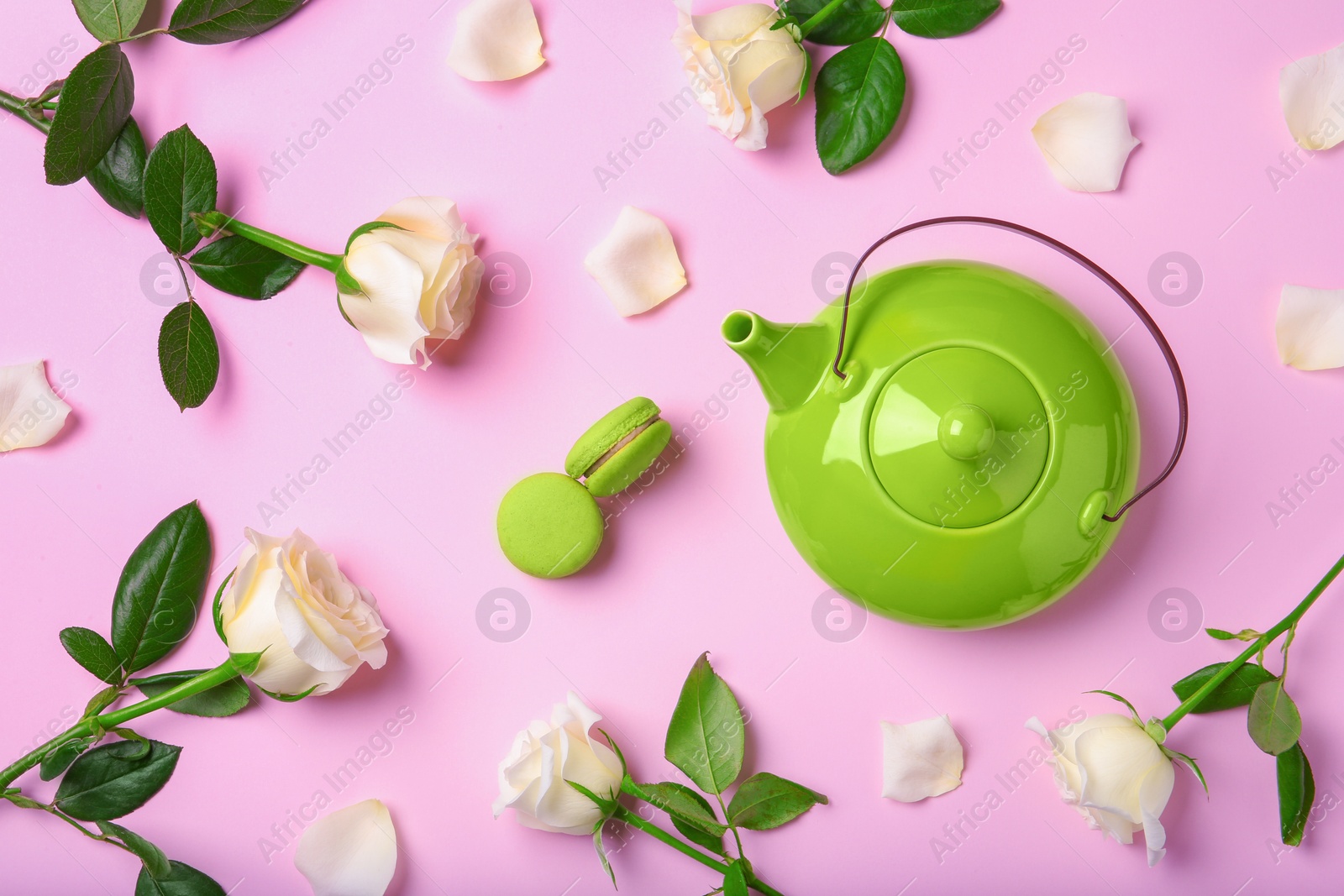 Photo of Flat lay composition with teapot, macarons and roses on color background