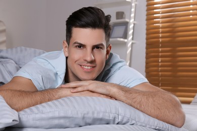 Photo of Man lying in comfortable bed with light grey striped linens