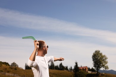 Photo of Man throwing boomerang outdoors on sunny day. Space for text
