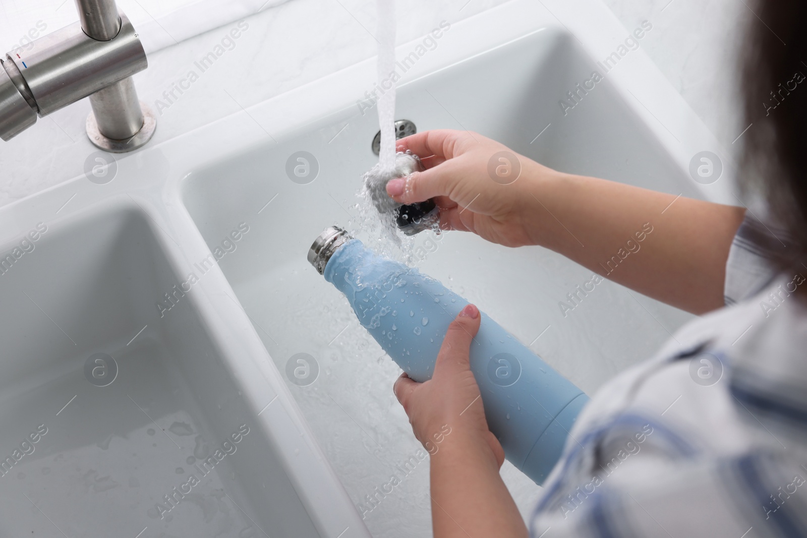 Photo of Woman washing thermo bottle in kitchen, above view
