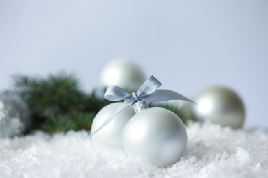 Photo of Beautiful Christmas balls on snow against grey background. Space for text