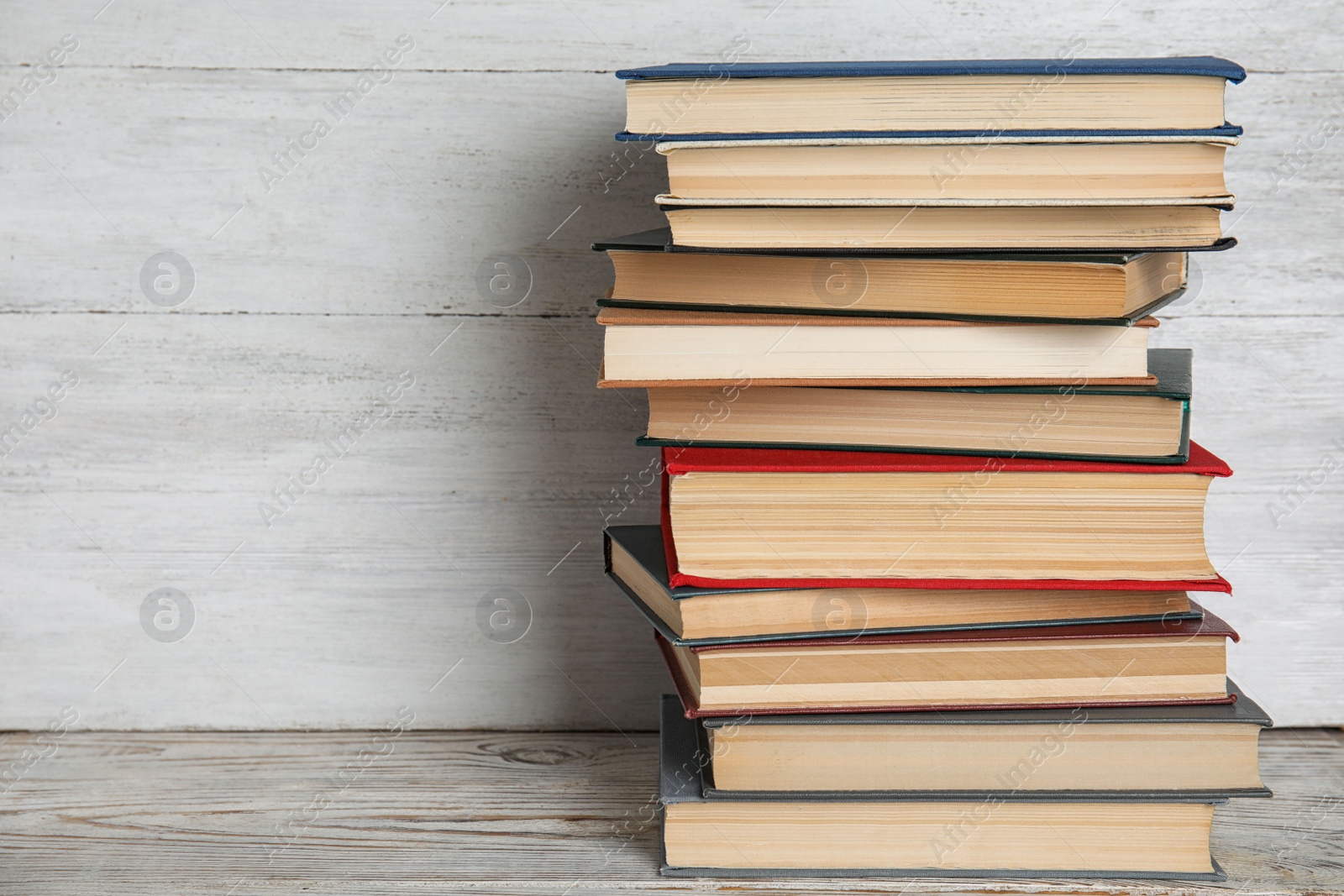 Photo of Stack of hardcover books on wooden table against white background. Space for text