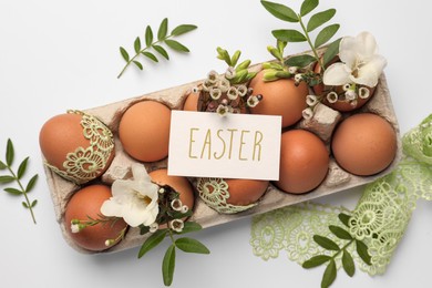 Card with word Easter, eggs and green twigs on white background, flat lay