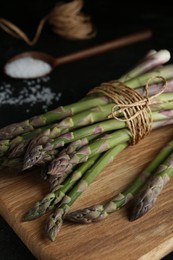 Photo of Raw green asparagus on wooden board, closeup
