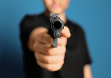 Photo of Man holding gun on blue background, closeup