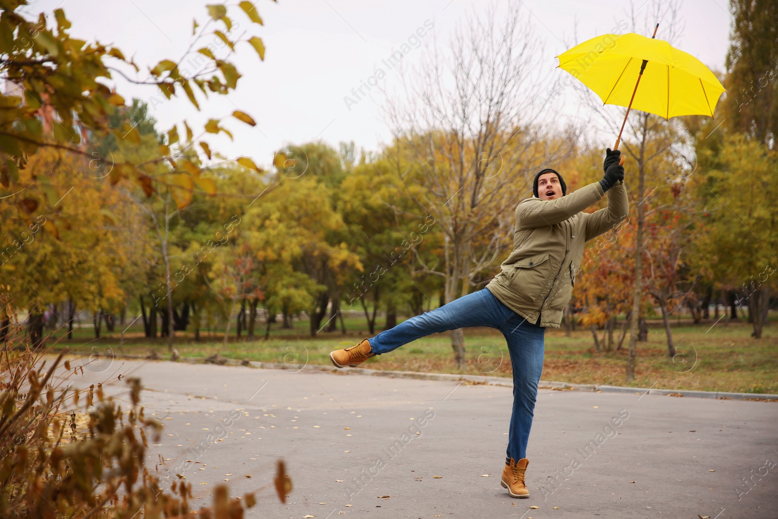 Photo of Man with yellow umbrella caught in gust of wind outdoors